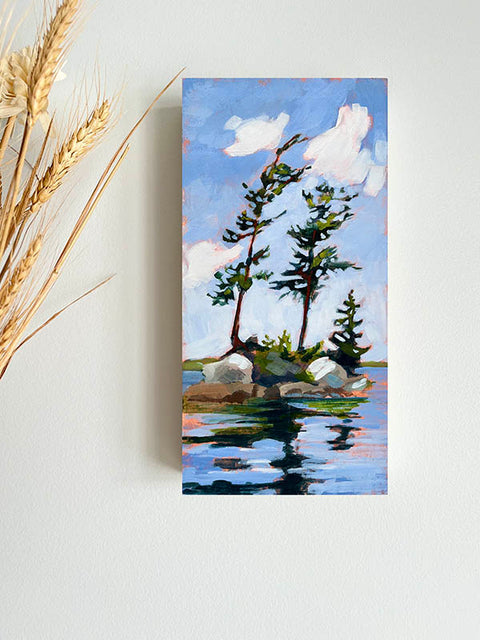 a landscape painting of pine trees growing on an island with blues skies and reflective water