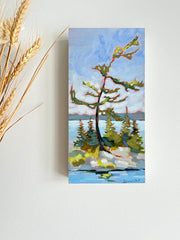 a Canadian landscape painting of a windswept tree on an island surrounded by blue water and skies