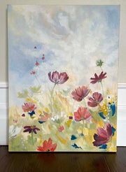 A floral oil painting of white, pink and red flowers in a field under a cloud filled blue sky
