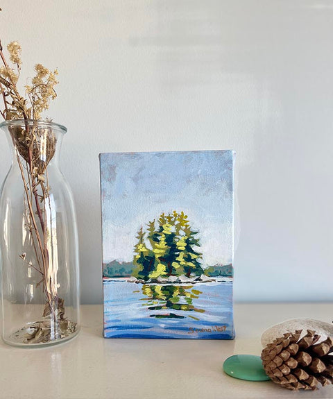 Canadian landscape painting of trees on an island surrounded by glistening blue water