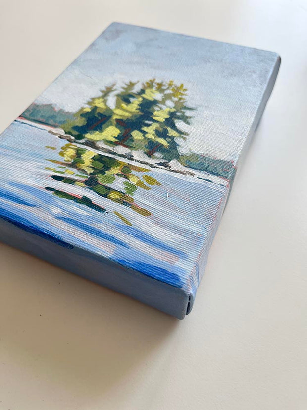Canadian landscape painting of trees on an island surrounded by shimmering blue water