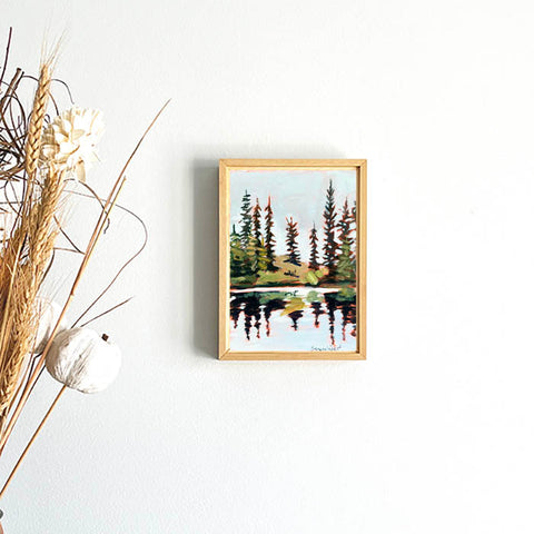 forest wall art in wooden frame of tall pines beside a shimmering lake