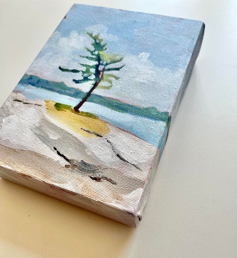 A landscape painting of a single pine tree grows by the edge of an Canadian lake